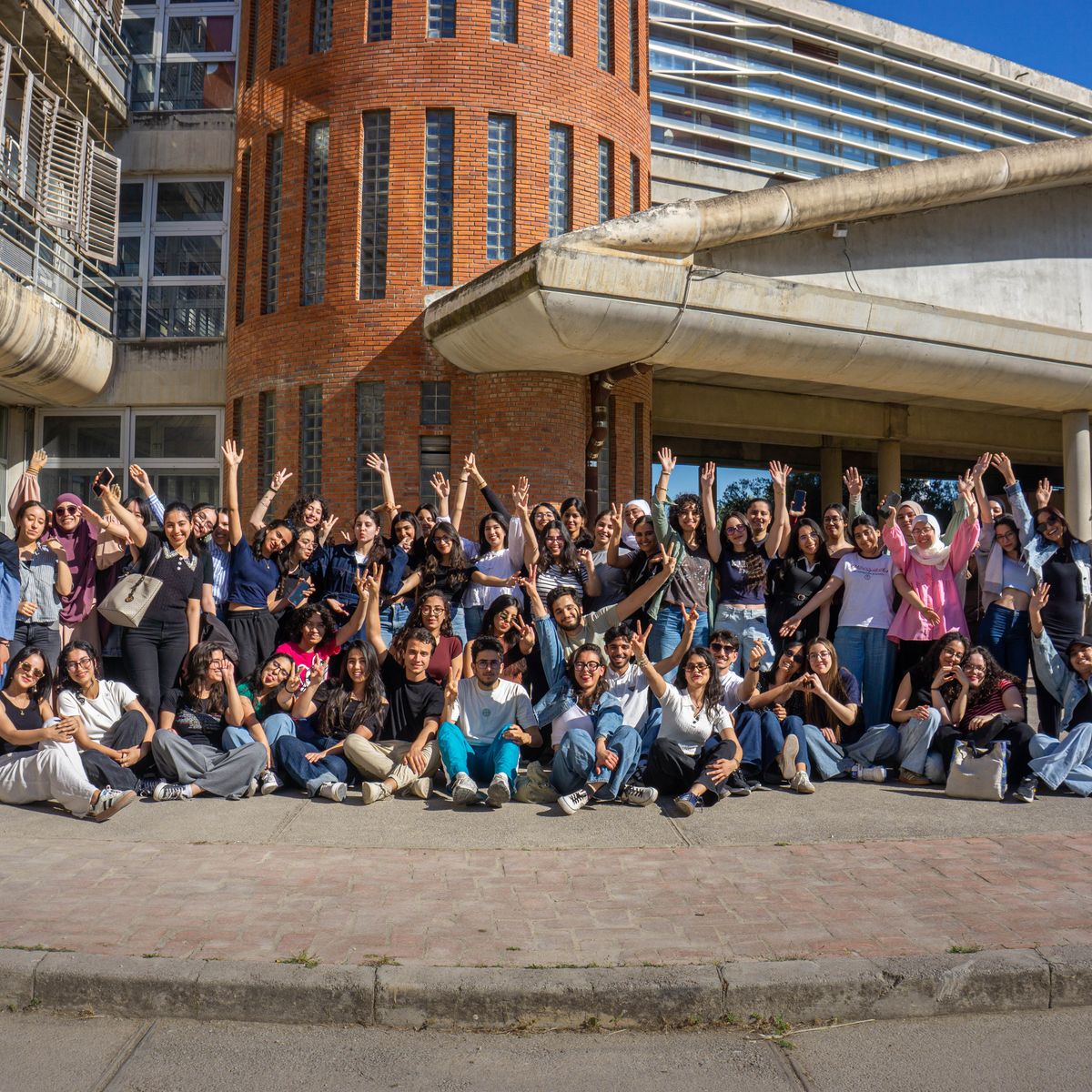 Diverse students celebrating in front of a modern campus